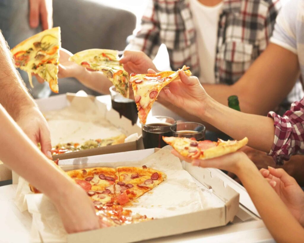 Friends sitting around the table eating pizza without fear of weight gain